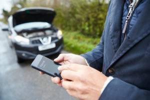 motorist calling for assistance in front of broken down vehicle