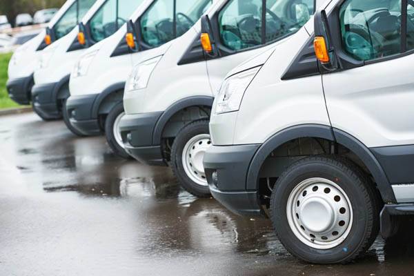 rank of identical white transit vans in a row