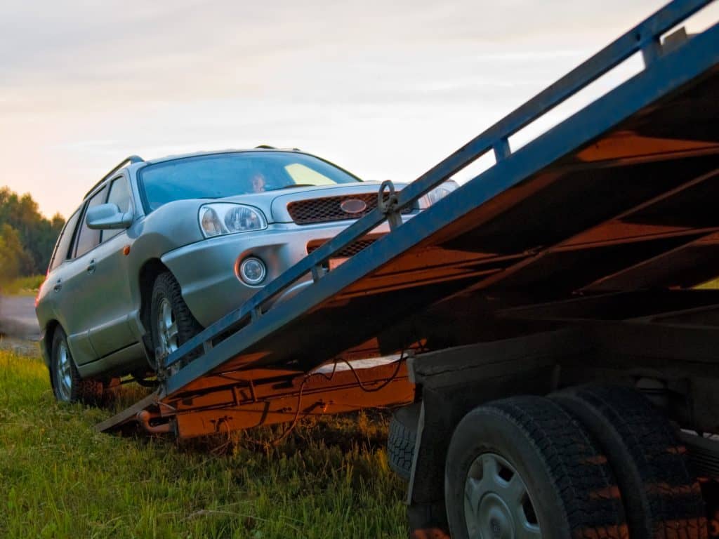 silver estate car diving up tow truck ramp