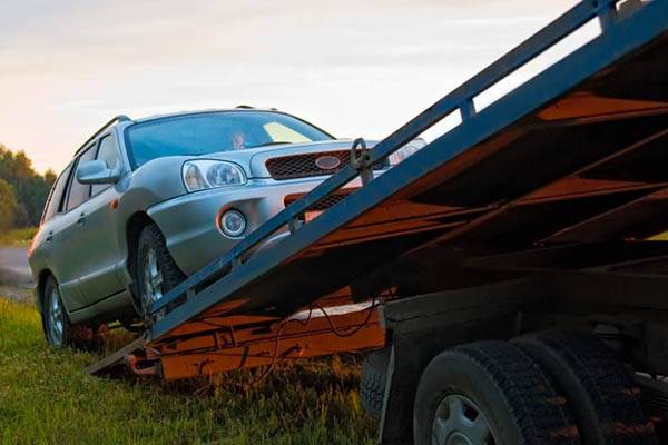 silver estate car diving up tow truck ramp